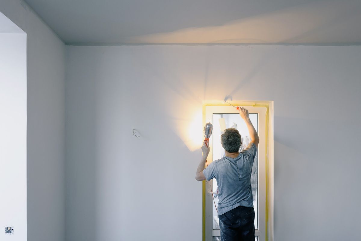 A tradesperson carefully painting a window frame